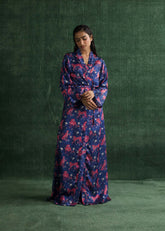 A women standing in a full-length shot, wearing a deep blue gown with vibrant pink tiger prints and a matching waist belt.